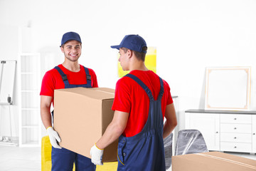 Male workers with boxes and furniture in new house