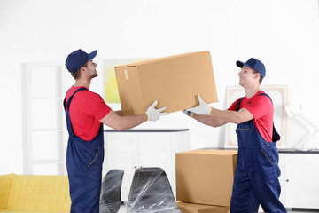 Male workers with boxes and furniture in new house