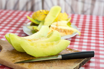Sliced melon on the kitchen wooden board and kitchen knife