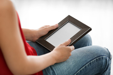 Female hands holding photo frame on light background