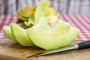 Sliced melon on the kitchen wooden board and kitchen knife
