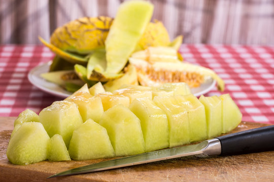 Sliced melon on the kitchen wooden board and kitchen knife
