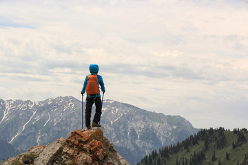 successful woman backpacker hiking on mountain peak cliff