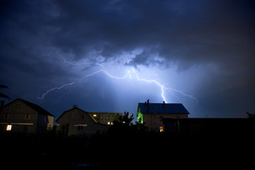 Fototapeta na wymiar Lightning in the cloudy sky over village