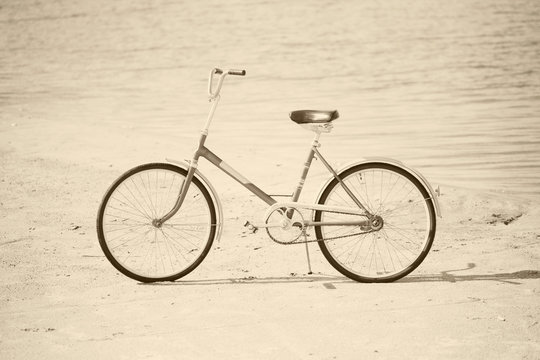 Ancient bicycle on beach - retro sepia