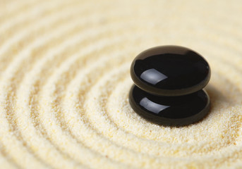 Fototapeta na wymiar Two black stones put in a pile on sand
