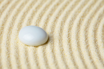 Fototapeta na wymiar Ceramic stone on a surface of yellow sand close up