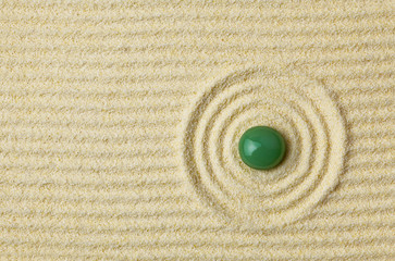 Fototapeta na wymiar Green stone on surface of yellow sand