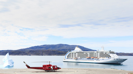red helicopter on landing beside cruise ship with big iceberg an