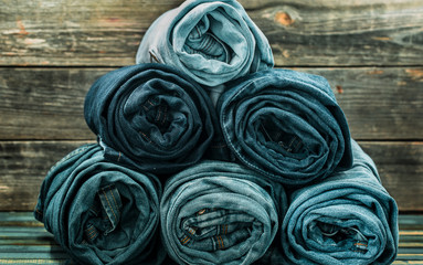 Fototapeta na wymiar bunch of jeans twisted on a wooden background, fashionable clothes