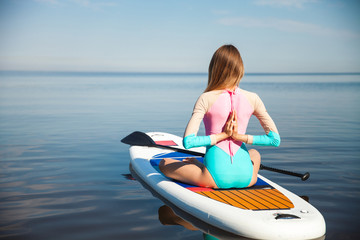 Fototapeta na wymiar Woman doing yoga on sup board with paddle
