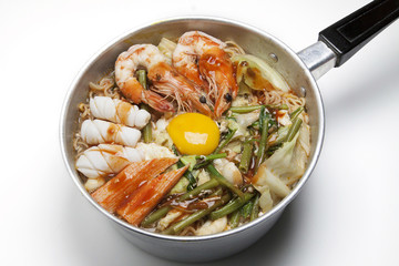 Pot of spicy instant noodles isolated on white background. Topping with eggs, lemon, pork , crispy pork, sausage , shrimp,Squid, crab and coriander