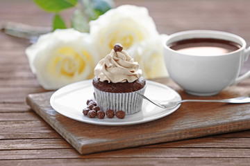 Tasty cupcake with roses on wooden table