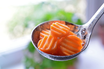 Sliced baby carrot in metal ladle closeup