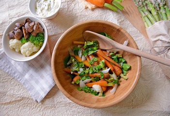 Fresh vegetable salad with baby carrot in wooden bowl, top view
