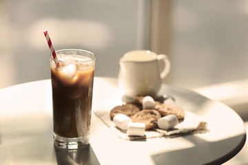 Iced coffee with straw on white table in cafe