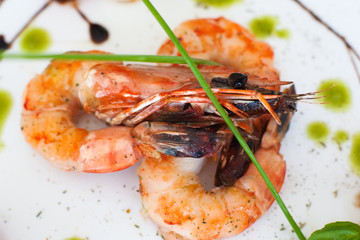 Grilled shrimps on white background, closeup. Three roasted prawns on dish, cooked seafood