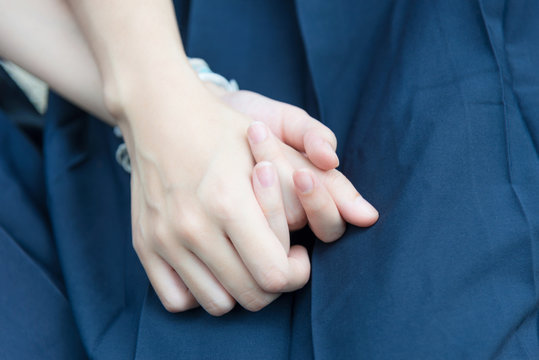 Hand of Asian Thai high schoolgirls student couple in school uniform holding hands with love and friendship on the lap with blue school uniform skirt 