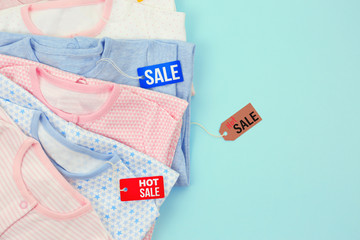 Baby clothes and tags on color background. Sale concept