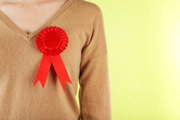 Woman with red award prize ribbon on color background