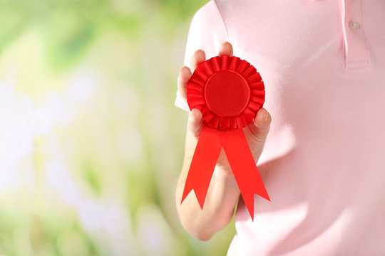 Woman holding red award prize ribbon on blurred background