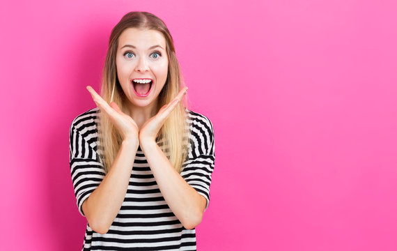 Happy young woman posing on pink background