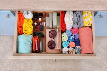 Fototapeta na wymiar Neatly folded clothes with accessories in chest of drawers