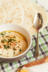 A bowl of creamy hummus with olive oil and pita chips.