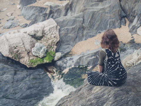 Woman sitting on rocks by creek