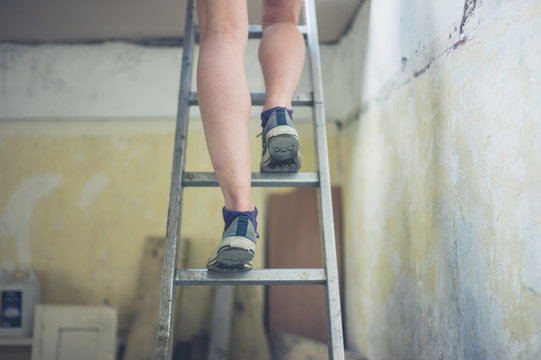 Legs of woman standing on ladder