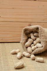 peanuts in sack on bamboo mats and wood background