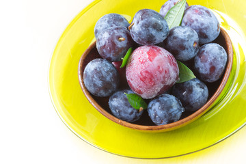 Fresh ripe plums in wooden bowl.