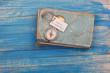 Sign Life is an adventure and Compass on old book - Vintage style