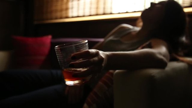 sad lonely woman drinks alcohol in the dark. Glass in sharp focus. female alcoholism