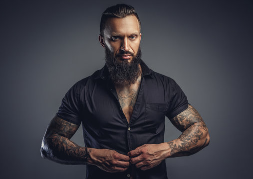 Tattooed bearded male taking off his shirt.