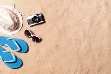 Fototapeta na wymiar Pair of flip flop sandals, sunglasses, hat and camera.