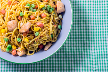Asian egg noodles with vegetables on green tablecloth.