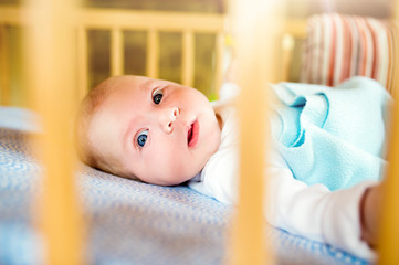 Little baby boy lying in wooden crib, close up