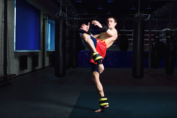 Sports: man kickboxer is practicing kick in a boxing gym