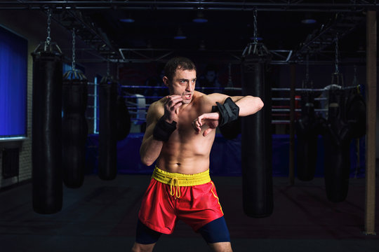 Sports: man kickboxer is practicing kick in a boxing gym