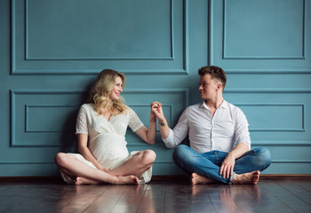 Husband and pregnant wife are sitting inside of their new home