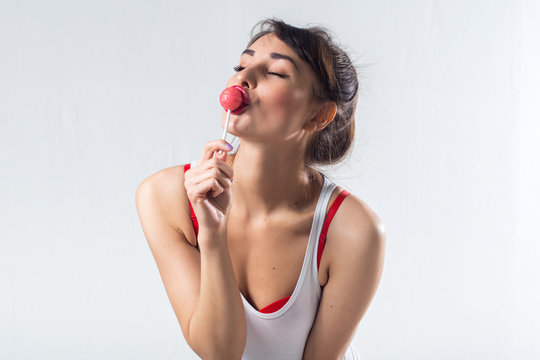 Young brunette model with lollipop posing studio shot on white background, not isolated