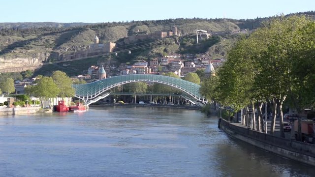 View of the River Kura, a glass bridge of the world, the cable car and Narikala Fortress. The movement cars on the road. Tbilisi

