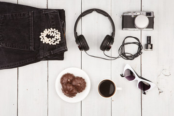 jeans, camera, headphones, sunglasses and coffee on white wooden desk