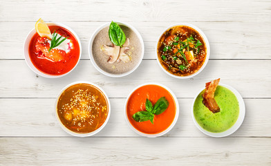 Variety of soups at white wood, top view