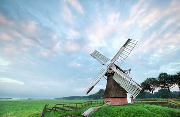 Fototapeta na wymiar old windmill on meadow in morning