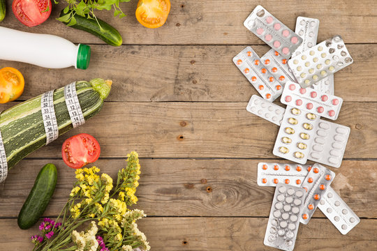 the choice between a healthy lifestyle and medications, vegetables or pills on brown wooden desk