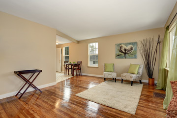 Cozy beige sitting room with shiny hardwood floor and dining area