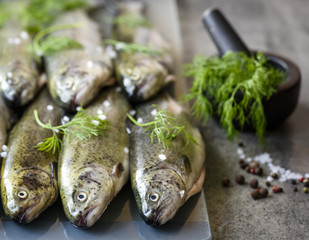 Rainbow trouts on a glass board and stone table with herbs 