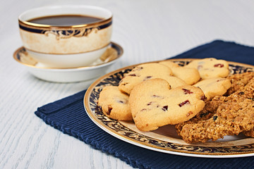 Dried-Cranberry Shortbread Hearts and Oatmeal Raisin Cookies With Coffee on a White Wooden Table
